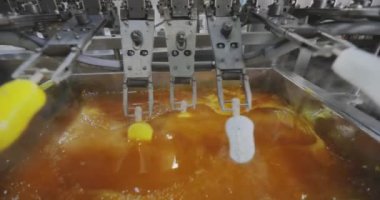 Ice cream is dipped into a container with fruit glaze. Colorful bright ice cream on the conveyor. Ice cream production.