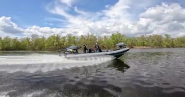 Bir devriye botu güzel bulutların arkaplanına karşı nehir boyunca yüzer. Tekne nehirde devriye geziyor. Hızlı bir devriye teknesi nehir boyunca yol alır.