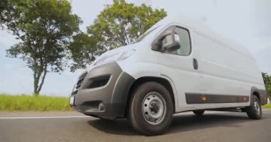 Kargo minibüsü güneşli bir havada otoyolda gidiyor. Beyaz kargo minibüsü otoban boyunca gidiyor.