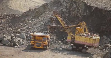 Büyük bir maden kazıcısı bir maden kamyonunu demir madenine yüklüyor.