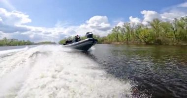 Bir devriye botu güzel bulutların arkaplanına karşı nehir boyunca yüzer. Tekne nehirde devriye geziyor. Hızlı bir devriye teknesi nehir boyunca yol alır.