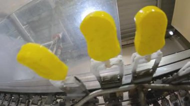 Ice cream is dipped into a container with fruit glaze. Colorful bright ice cream on the conveyor. Ice cream production.