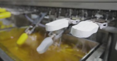 Ice cream is dipped into a container with fruit glaze. Colorful bright ice cream on the conveyor. Ice cream production.