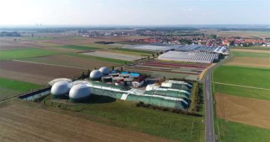 Yeşil tarlalardaki biyogaz fabrikası ve çiftliği. Biyokütlenin yenilenebilir enerjisi. Modern tarıma havadan bakış