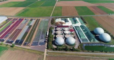 Yeşil tarlalardaki biyogaz fabrikası ve çiftliği. Biyokütlenin yenilenebilir enerjisi. Modern tarıma havadan bakış