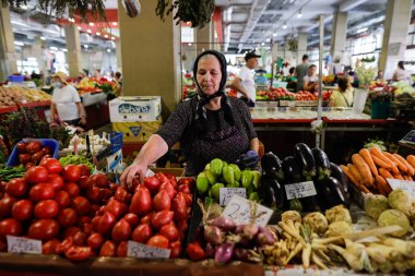 Bükreş, Romanya - 4 Ağustos 2022: Romanya 'nın Bükreş kentindeki Obor pazarında sebze satan üst düzey bir kadınla sığ alan derinliği (seçici odak) ayrıntıları.