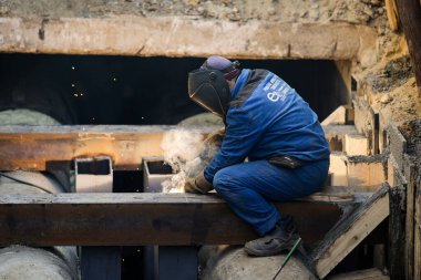 Bükreş, Romanya - 10 Kasım 2022: Sanayi metalik boru hattını kaynak yapan profesyonel bir kaynakçıyla ayrıntılar.