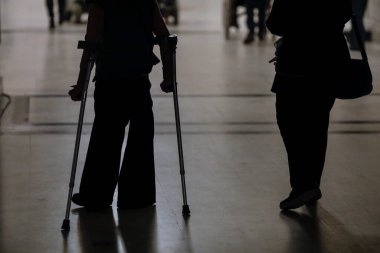 Koltuk değneği kullanan bir kadının yüzeysel derinliği (seçici odak) silueti.