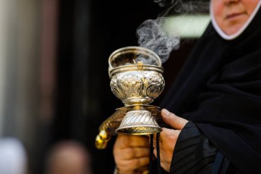 Ortodoks Hıristiyan rahibenin elinde tütsü tütsüsü tutarken sığ alan derinliği (seçici odak) ayrıntıları