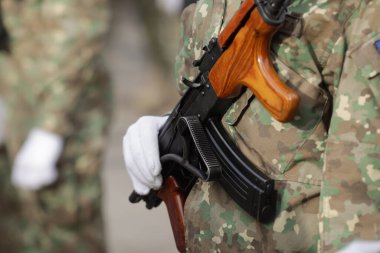 Bir Romen askerinin elinde bir AK47 tüfeğinin namlusuyla sığ alan derinliği (seçici odak) ayrıntıları.