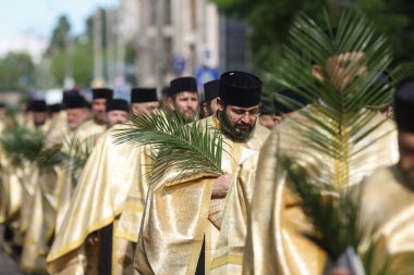 Bükreş, Romanya - 27 Nisan 2024: Palmiye yaprakları tutan Romen Ortodoks rahipler Pazar günü düzenlenen bir hac alayında Bükreş sokaklarında yürüyorlar.