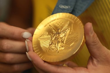 Otopeni, Romania - August 7, 2024: Details with the hands of a Romanian athlete holding a gold medal won at the Paris 2024 Olympics. clipart