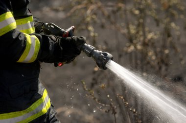 Yangın söndürme hortumunu kullanarak bir itfaiyecinin ellerindeki detaylar..