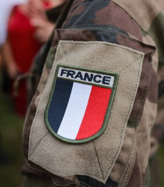 Shallow depth of field (selective focus) details with the French flag on the military uniform of a soldier. clipart