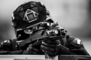 Shallow depth of field (selective focus) details with a weapon being aimed by a special forces soldier.