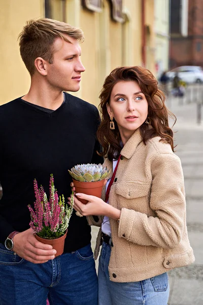 stock image Man and woman holding a purple sempervivum succulent plant and blooming violet heather plant. Romantic moment.