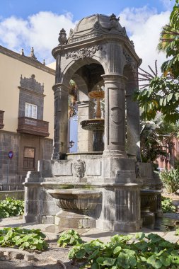 Vegueta, Las Palmas de Gran Canaria, İspanya 'daki Plaza del Espiritu Santo' da ortaçağ mimarisi ve palmiye ağaçları bulunan açık hava çeşmesi.
