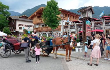 Leavenworth 'un renkli Bavyera temalı köyünde at arabası ve turistler - 20 Mayıs 2023, Leavenworth, Washington eyaleti, ABD