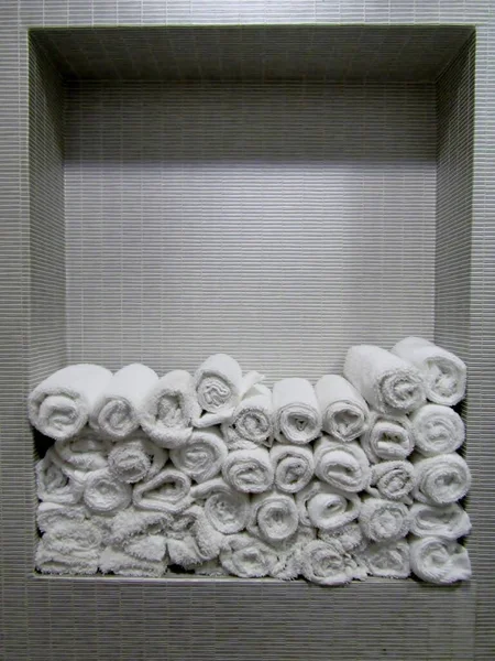 卫生间架子上的瓷砖上铺着滚白柔软的手巾 — 图库照片