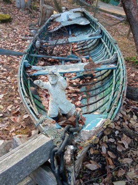 Heykelciği düşmüş sonbahar yapraklarıyla kaplı eski bir balıkçı teknesi.