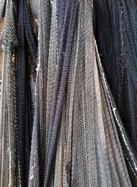 Duvarda asılı siyah, gri ve mor düğümlü naylon balıkçı ağı