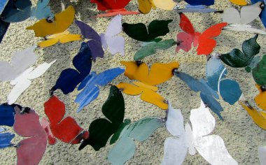 Beyaz duvardaki kullanılmış boya kutularından yapılmış renkli kelebekler.