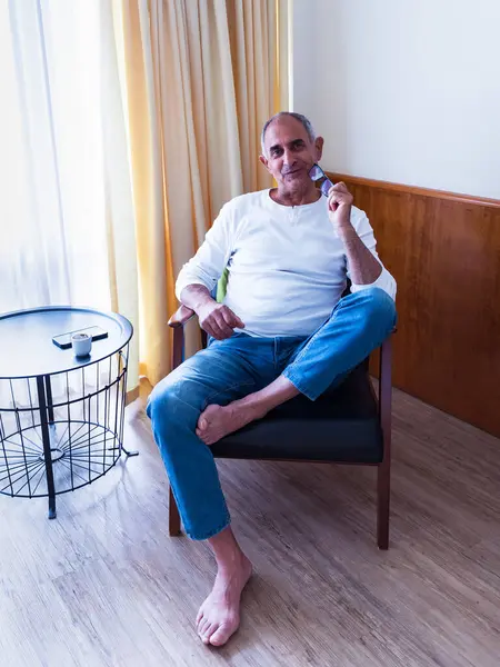 Rahat bir evde tek başına oturan olgun bir adam okuma gözlüğü tutarken dalgın dalgın bakıyor. Bir akıllı telefon ve kahve fincanı yanındaki küçük masada dinleniyor. Sakin ve içsel yaşam tarzı anı.