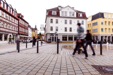 Sıcak güneşli bir günde Coburg Bavyera 'da Albertplatz' da çocuklu bulanık bir kadın aile hayatını ve rahat şehir atmosferini gösteren tarihi binalarla yürüyor.