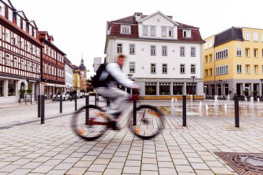 Hareket halindeki bisiklet sürücüsü Coburg Bavyera 'da Albertplatz Meydanı' ndan geçerken bulanıklaşıyor. Parlak bahar veya yaz gününde arka planda tarihi binalar çevre dostu kentsel taşımacılığı gösteriyor.