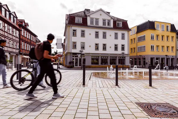 Güneşli bir günde Coburg Bavyera 'da Albertplatz' da bisikletle yürüyen bulanık gençler. Arka planda tarihi mimari gelişigüzel şehir yaşam tarzını ve kentsel enerjiyi gösteriyor.