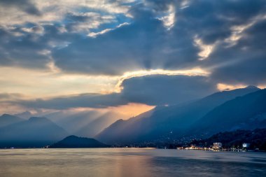 late evening in summer at lake como with hazy mountains and sunbeams shining through clouds