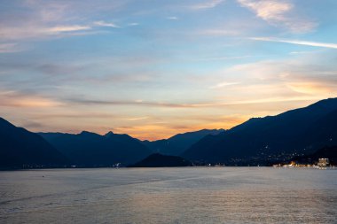 just after sunset on lake como with the lights of villages visible across the water