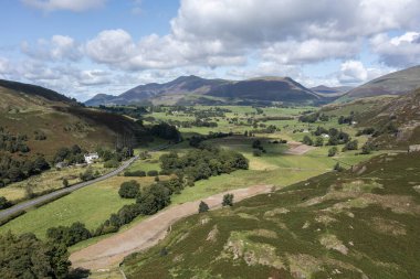Keswick Gölü yakınlarındaki Skiddaw ve Blencathra hava manzaralı Castlerigg sol tarafa düştü ve sağdaki yüksek Riggs orta mesafede güneşli yaz gününde