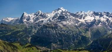Bernese Oberland 'deki Murren köyünün yukarısındaki Eiger Monch ve Jungfrau dağları güneşli mavi gökyüzü.