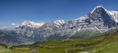 Bernese Oberland 'daki Grindelwald köyünün yukarısındaki Eiger Schreckhorn ve Wetterhorn Dağları güneşli mavi gökyüzü manzarası