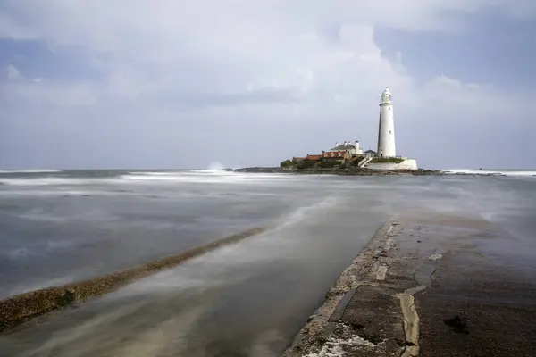 stock image st marys lighthouse whitley bay tyneside uk from the causeway at high tide with blurred motion of waves