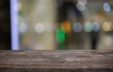 Kafenin soyut bulanık arka planının önündeki boş ahşap masa. Öndeki ahşap tablo ürünlerinizi görüntülemek veya montajlamak için kullanılabilir. Produc gösterimi için modelleyin