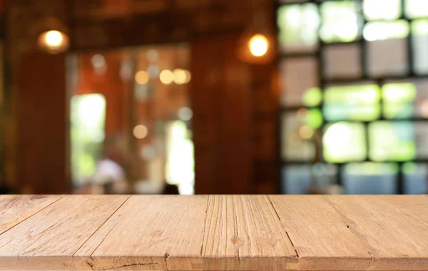 Empty wooden table in front of abstract blurred background of coffee shop . wood table in front can be used for display or montage your products.Mock up for display of produc