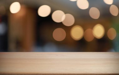 Kafenin soyut bulanık arka planının önündeki boş ahşap masa. Öndeki ahşap tablo ürünlerinizi görüntülemek veya montajlamak için kullanılabilir. Produc gösterimi için modelleyin