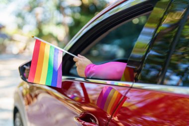 Happy Asian woman support LGBT pride parade in car. with Rainbow of LGBTQ or LGBTQIA