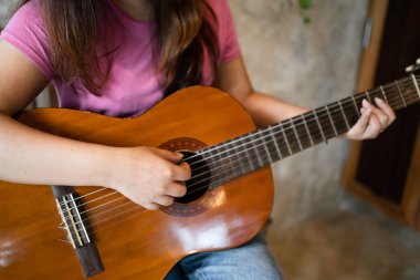Sadece akustik gitar çalan mutlu genç kadın elleri gitar çalmak üzerine enstrümantal şarkı dersi yazar..