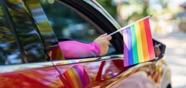Happy Asian woman support LGBT pride parade in car. with Rainbow of LGBTQ or LGBTQIA