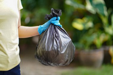 Gönüllü hayırsever kadın elinde çöp torbası ve plastik şişe çöpü ile parktaki gönüllü temizlikçi konseptini yeniden kullanacak ve gönüllü olacak.