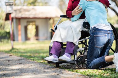 Huzurevi. Genç bakıcı tekerlekli sandalyedeki yaşlı kadına yardım ediyor.