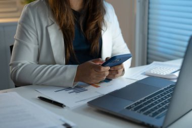 Gece geç saatlere kadar çalışmak. İş yerindeki Asyalı iş kadını gecenin geç saatlerinde karanlık bir ofiste masa başında bilgisayarla çalışıyor..
