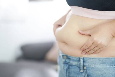 Şişman kadın karnı için üzülüyor. Kilolu bir kadın şişman karnına dokunuyor ve kilo vermek istiyor. Dar elbiseli şişman kadın kilo diyeti yaşam tarzı konsepti hakkında endişeli..