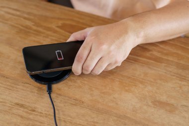 Charging mobile phone battery with wireless charging device in the table. Smartphone charging on a charging pad. Mobile phone near wireless charger Modern lifestyle technology concept
