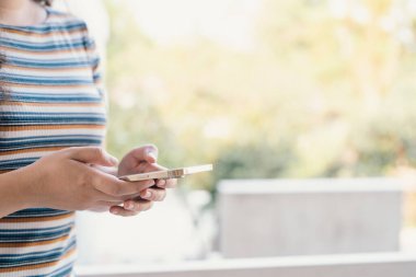 Sosyal medyayı kontrol eden bir kadın evde akıllı telefon tutuyor. Erkek arkadaşı ya da arkadaşıyla sohbet ediyor..