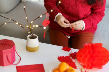 Asian Woman decorated house for Chinese New Year Celebrations. putting traditional pendant to the Chinese Lunar New Year for good luck. Chinese word means blessing.