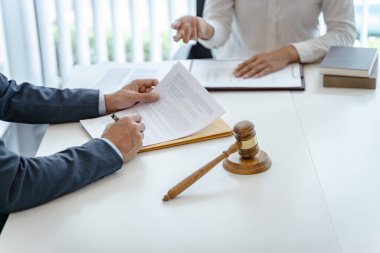 Avukat hukuk danışmanı müvekkiline tokmak ve hukuk hukuku ile imzalanmış bir sözleşme sunar. Adalet ve Avukat İş ortaklığı toplantısı